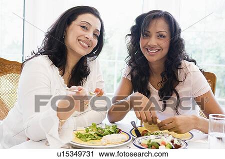 Two women sitting at dinner table smiling (high key) View Large Photo Image Stock Image - Two women sitting at dinner table smiling (high key). Fotosearch