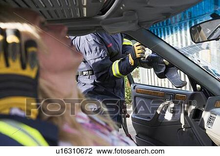 Firefighter cutting out a windshield after an accident with injured woman in foreground (selective focus) View Large Photo Image Stock Image - Firefighter cutting out a windshield after an accident with injured woman in foreground (selective focus). Fotosearch
