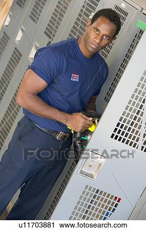 Stock Image - Fireman getting his helmet out of his locker in fire station locker room (depth of field). Fotosearch