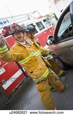 Fireman motioning for backup with another fireman using the jaws of life on a car door (blur) View Large Photo Image Stock Image - Fireman motioning for backup with another fireman using the jaws of life on a car door (blur). Fotosearch