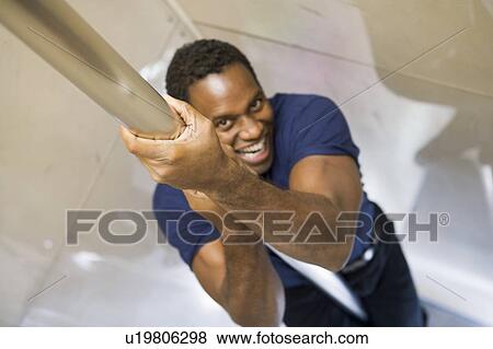 Stock Photo - Fireman sliding down fire pole smiling (selective focus). Fotosearch