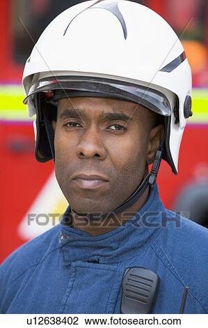 Fireman standing by fire engine wearing helmet View Large Photo Image Stock Image - Fireman standing by fire engine wearing helmet. Fotosearch