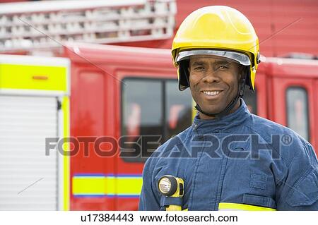 Fireman standing by fire engine wearing helmet View Large Photo Image Stock Image - Fireman standing by fire engine wearing helmet. Fotosearch