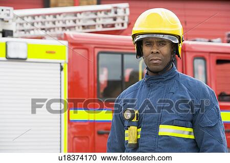 Fireman standing by fire engine wearing helmet View Large Photo Image Stock Image - Fireman standing by fire engine wearing helmet. Fotosearch