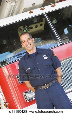 Stock Photo - Fireman standing in front of fire engine. Fotosearch