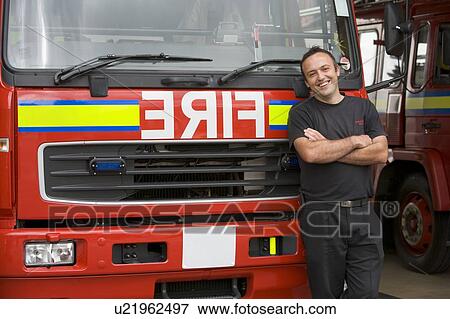 Stock Photo - Fireman standing in front of fire engine. Fotosearch
