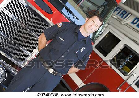 Stock Photograph - Fireman standing in front of fire engines. Fotosearch