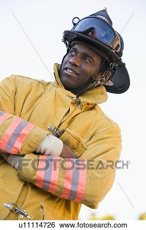 Fireman standing outdoors wearing helmet View Large Photo Image Stock Photograph - Fireman standing outdoors wearing helmet. Fotosearch