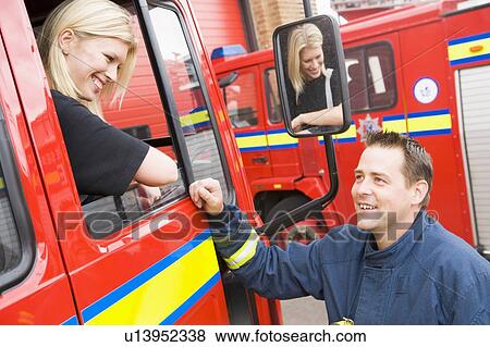 Stock Photo - Firewoman sitting in fire engine talking to fireman standing outside. Fotosearch