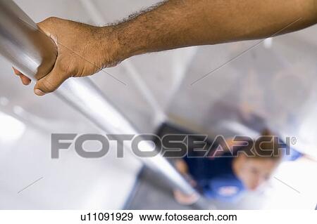 Stock Photo - Shot of fireman's hand on a fire pole with firewoman at bottom (selective focus). Fotosearch