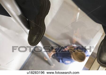 Stock Photograph - Shot of fireman's legs on a fire pole with firewoman at bottom (selective focus). Fotosearch