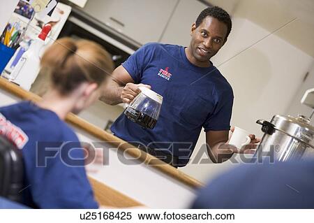 Stock Photography - Three firefighters in break room with one getting coffee (selective focus). Fotosearch