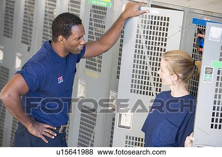 Stock Photo - Two firefighters in locker room talking (depth of field). Fotosearch
