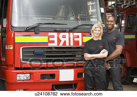 Two firefighters standing in front of fire engine View Large Photo Image Stock Image - Two firefighters standing in front of fire engine. Fotosearch