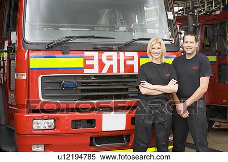 Two firefighters standing in front of fire engine View Large Photo Image Stock Photography - Two firefighters standing in front of fire engine. Fotosearch