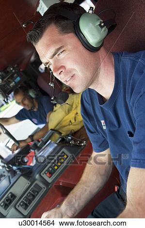 Picture - Two firemen in fire engine (selective focus). Fotosearch
