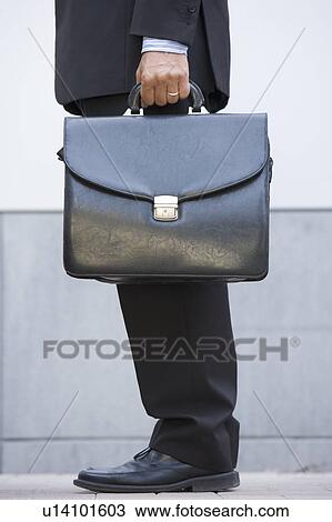 Businessman holding briefcase outdoors View Large Photo Image Stock Image - Businessman holding briefcase outdoors. Fotosearch