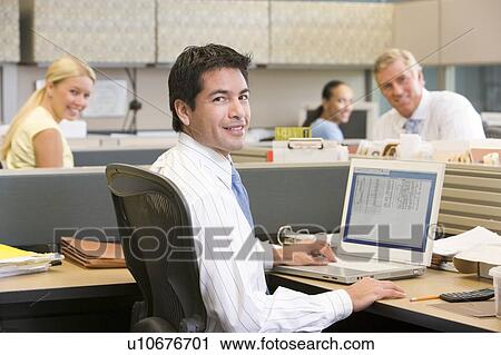 Businessman in cubicle with laptop smiling View Large Photo Image Stock Image - Businessman in cubicle with laptop smiling. Fotosearch