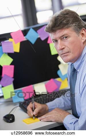 Businessman in office at monitor with notes on it writing View Large Photo Image Stock Photograph - Businessman in office at monitor with notes on it writing. Fotosearch