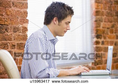 Stock Photo - Businessman sitting in office with laptop. Fotosearch