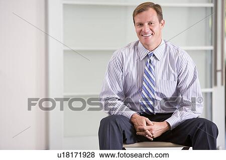 Stock Photo - Businessman sitting indoors smiling. Fotosearch