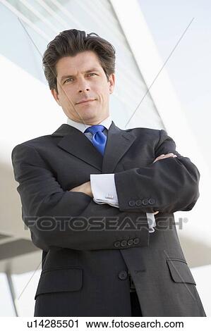 Stock Image - Businessman standing outdoors by building. Fotosearch