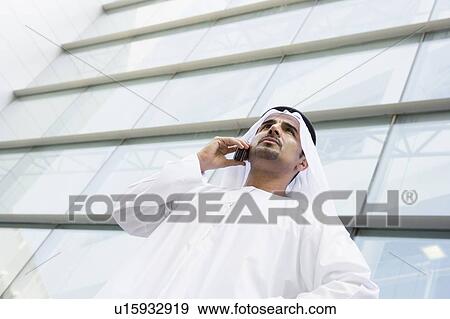Businessman standing outdoors by building on cellular phone (selective focus) View Large Photo Image Stock Photo - Businessman standing outdoors by building on cellular phone (selective focus). Fotosearch