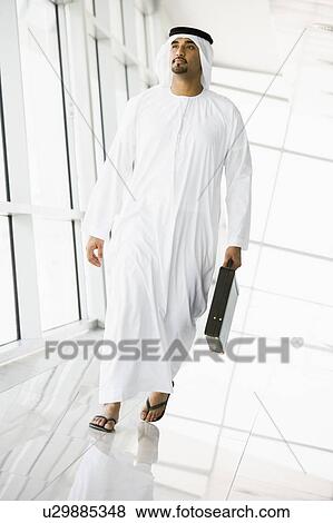Stock Photo - Businessman walking in a corridor with a briefcase (high key/selective focus). Fotosearch