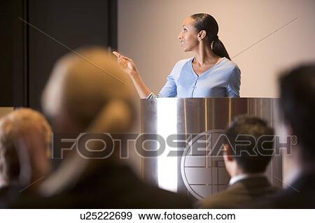 Stock Photo - Businesswoman giving presentation at podium. Fotosearch