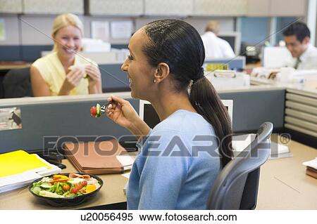 Businesswoman in cubicle eating salad and smiling View Large Photo Image Stock Photography - Businesswoman in cubicle eating salad and smiling. Fotosearch