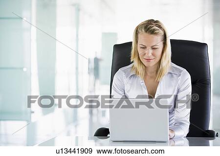 Stock Photo - Businesswoman in office using laptop. Fotosearch
