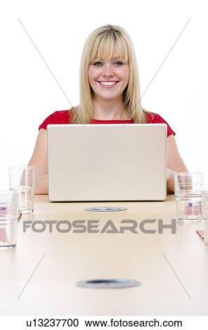 Businesswoman sitting in boardroom with laptop smiling View Large Photo Image Stock Image - Businesswoman sitting in boardroom with laptop smiling. Fotosearch
