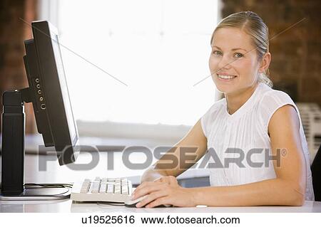 Businesswoman sitting in office with computer smiling View Large Photo Image Stock Photograph - Businesswoman sitting in office with computer smiling. Fotosearch
