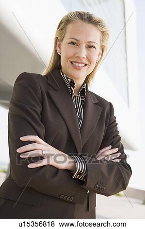 Stock Photo - Businesswoman standing outdoors by building smiling. Fotosearch