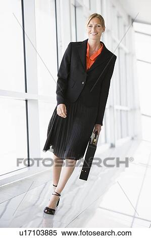 Stock Photography - Businesswoman walking in corridor smiling. Fotosearch