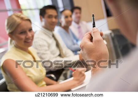 Stock Photo - Five businesspeople at boardroom table with focus on businessman's pen. Fotosearch