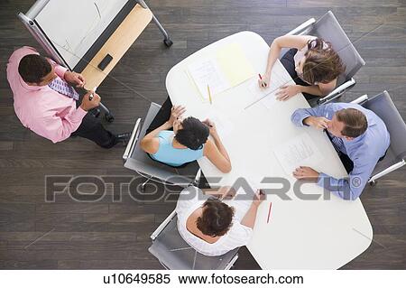 Four businesspeople at boardroom table watching presentation View Large Photo Image Stock Photography - Four businesspeople at boardroom table watching presentation. Fotosearch