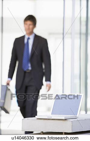 Laptop sitting in office lobby with businessman walking in View Large Photo Image Stock Image - Laptop sitting in office lobby with businessman walking in. Fotosearch