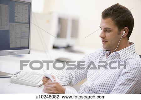 Man in computer room listening to MP3 player View Large Photo Image Stock Image - Man in computer room listening to MP3 player. Fotosearch
