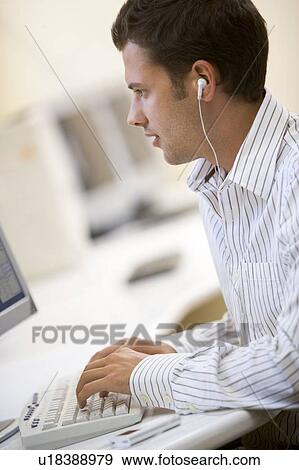Man in computer room listening to MP3 player while typing View Large Photo Image Stock Photo - Man in computer room listening to MP3 player while typing. Fotosearch