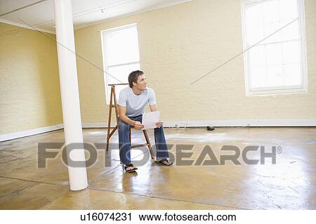 Man sitting on ladder in empty space holding paper smiling View Large Photo Image Stock Image - Man sitting on ladder in empty space holding paper smiling. Fotosearch