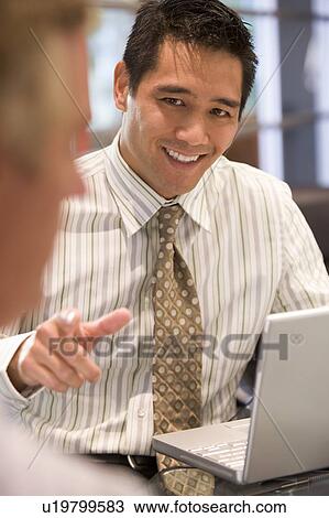 Two businessmen in boardroom with laptop talking View Large Photo Image Stock Image - Two businessmen in boardroom with laptop talking. Fotosearch