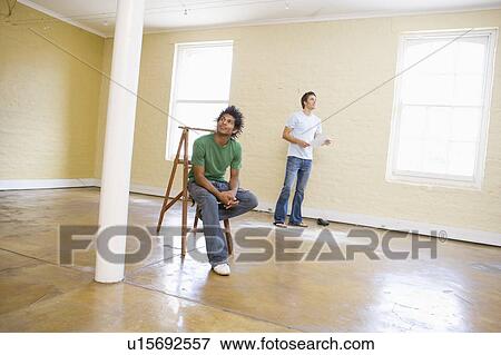 Stock Photo - Two men with ladder in empty space holding paper and thinking. Fotosearch
