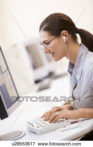 Woman in computer room listening to MP3 Player while typing and smiling View Large Photo Image Stock Photo - Woman in computer room listening to MP3 Player while typing and smiling. Fotosearch