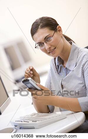 Woman in computer room using personal digital assistant and smiling View Large Photo Image Stock Photo - Woman in computer room using personal digital assistant and smiling. Fotosearch