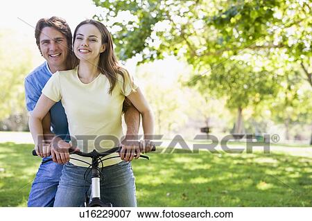 Couple on a bike outdoors smiling View Large Photo Image Stock Photo - Couple on a bike outdoors smiling. Fotosearch