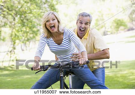Couple on bike outdoors smiling and acting scared View Large Photo Image Stock Photo - Couple on bike outdoors smiling and acting scared. Fotosearch