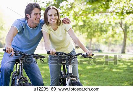 Couple on bikes outdoors smiling View Large Photo Image Stock Photo - Couple on bikes outdoors smiling. Fotosearch