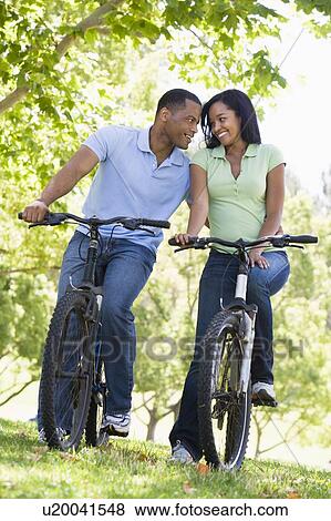 Couple on bikes outdoors smiling View Large Photo Image Stock Photo - Couple on bikes outdoors smiling. Fotosearch