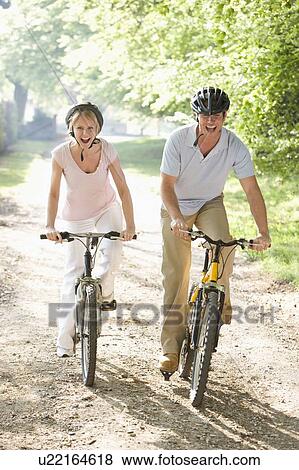 Stock Photo - Couple on bikes outdoors smiling. Fotosearch